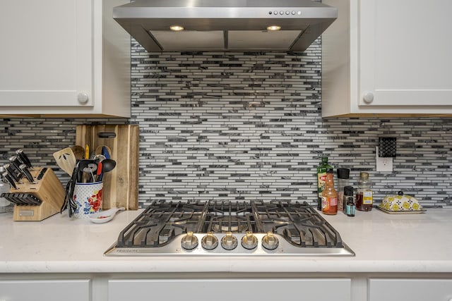 kitchen with tasteful backsplash, wall chimney exhaust hood, stainless steel gas stovetop, and white cabinets