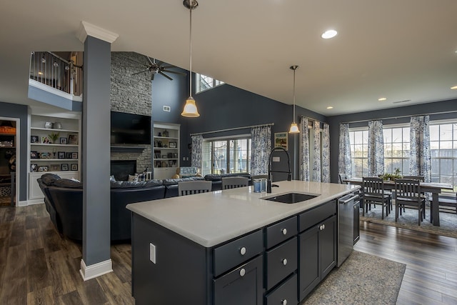 kitchen featuring dark wood-style floors, a fireplace, light countertops, stainless steel dishwasher, and a sink