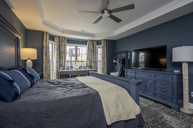 bedroom with a tray ceiling, a ceiling fan, visible vents, and crown molding