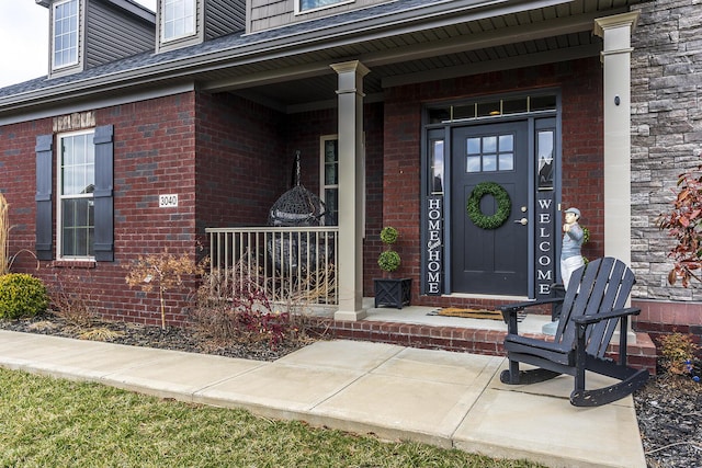 view of exterior entry with a porch and brick siding