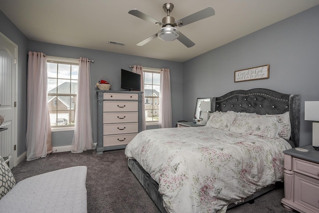 bedroom featuring visible vents, dark carpet, baseboards, and multiple windows