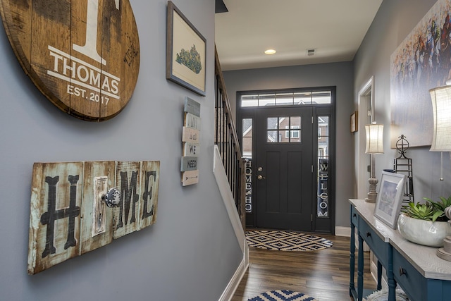 foyer with stairway, dark wood finished floors, visible vents, and baseboards