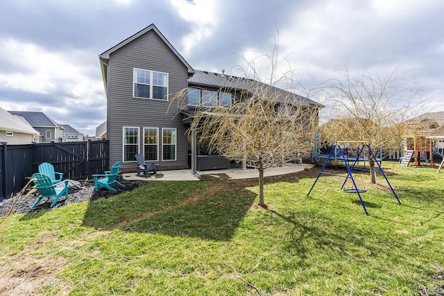 back of house with a yard, a playground, a patio, and a fenced backyard