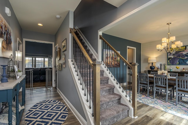 stairway with a notable chandelier, baseboards, and wood finished floors