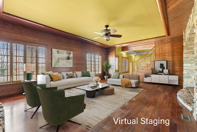 living room with visible vents, a ceiling fan, wood-type flooring, stairs, and wood walls