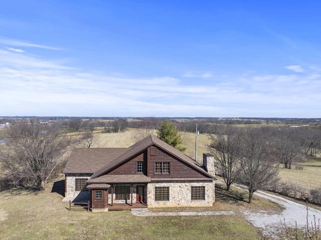 view of front of home featuring stone siding, a chimney, and roof with shingles