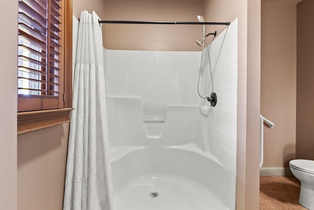 full bath featuring baseboards, toilet, and a shower with shower curtain