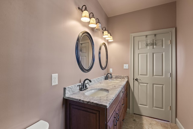 bathroom with double vanity, tile patterned flooring, baseboards, and a sink