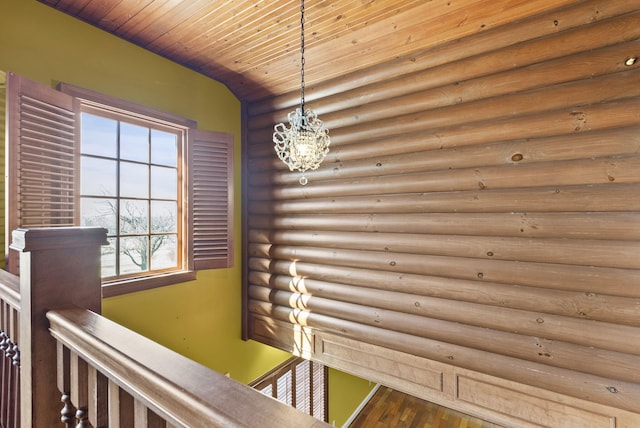 interior space with wood ceiling, a notable chandelier, an upstairs landing, and wood finished floors