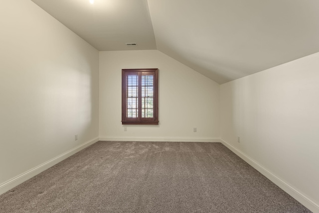 bonus room with dark colored carpet, visible vents, vaulted ceiling, and baseboards