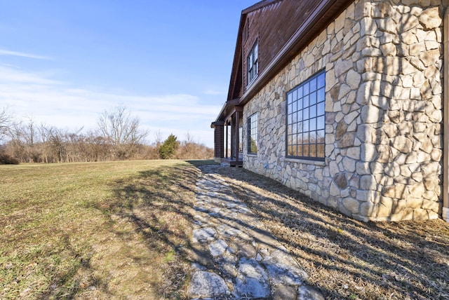 view of side of property featuring stone siding and a lawn