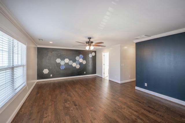 unfurnished room with visible vents, crown molding, baseboards, an accent wall, and wood finished floors