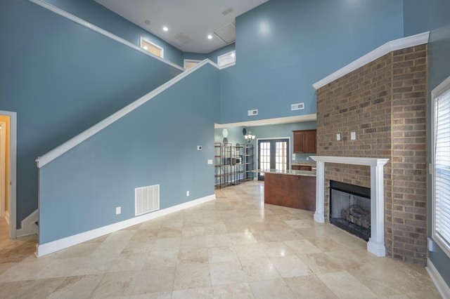 unfurnished living room with visible vents, baseboards, and a high ceiling