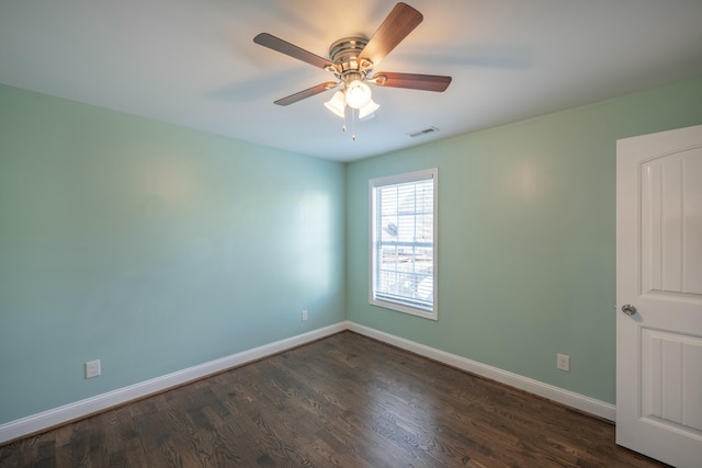 spare room featuring dark wood-style floors, visible vents, a ceiling fan, and baseboards