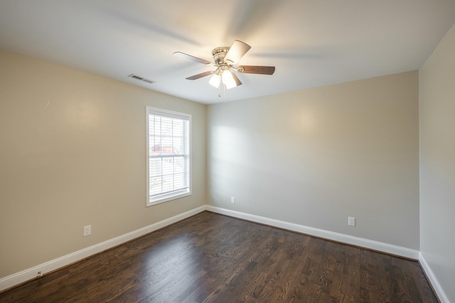 spare room with a ceiling fan, baseboards, visible vents, and dark wood-style flooring