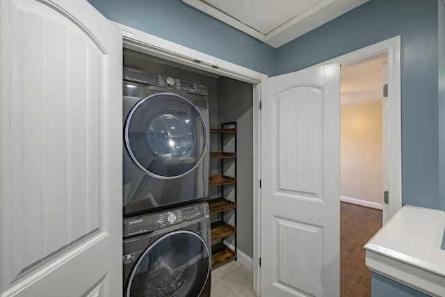 clothes washing area featuring laundry area, stacked washing maching and dryer, and baseboards