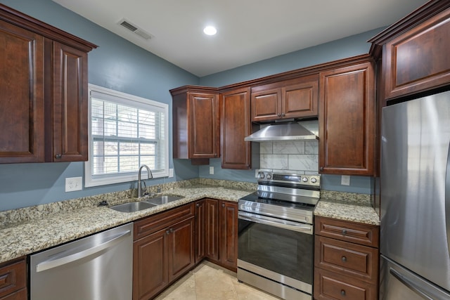 kitchen featuring visible vents, under cabinet range hood, light stone counters, a sink, and appliances with stainless steel finishes