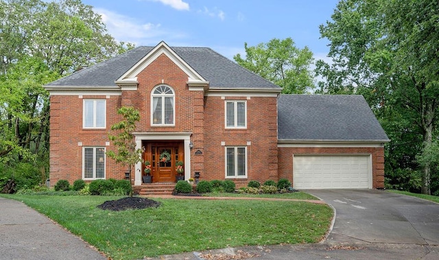 colonial home featuring concrete driveway, brick siding, an attached garage, and a shingled roof