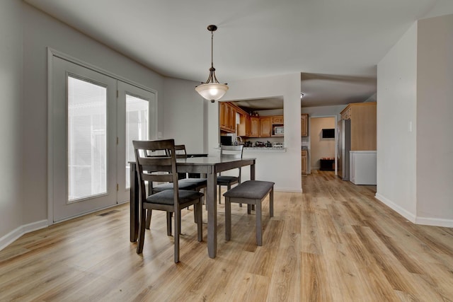 dining room with light wood-type flooring, visible vents, and baseboards