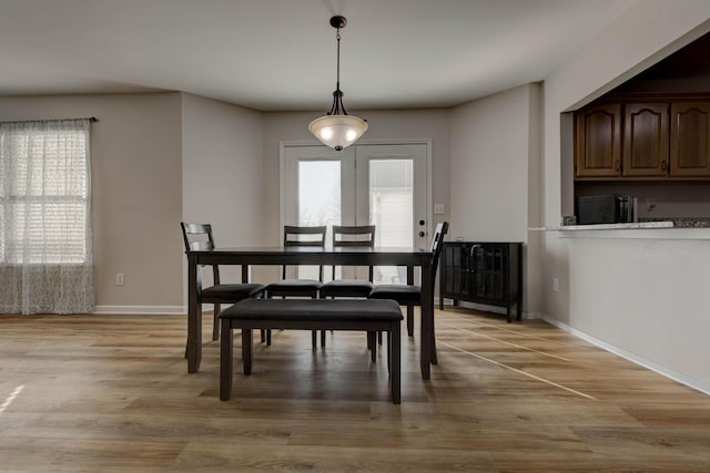 dining area with light wood-style floors, a wealth of natural light, and baseboards