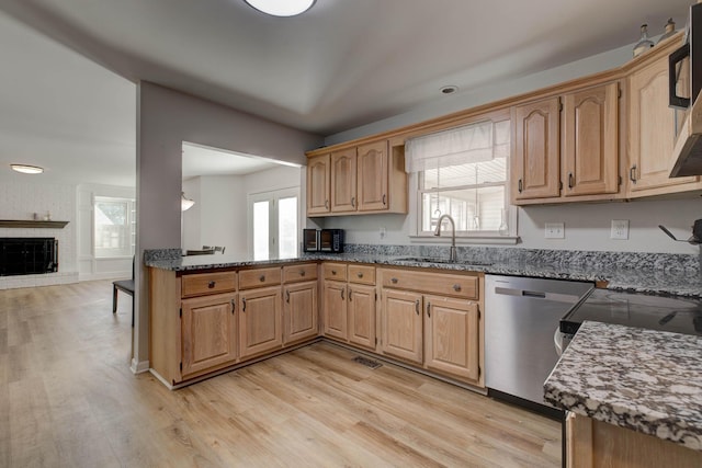 kitchen featuring light wood-type flooring, dark stone countertops, and dishwasher