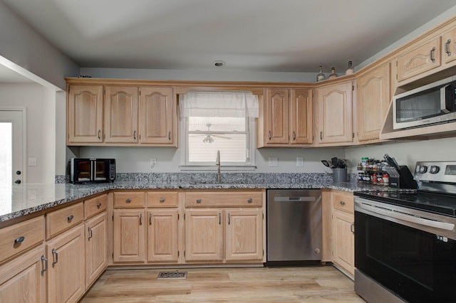 kitchen featuring light stone counters, light brown cabinets, stainless steel appliances, a sink, and visible vents