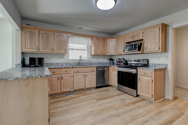 kitchen with light wood-style floors, stainless steel appliances, and light brown cabinetry