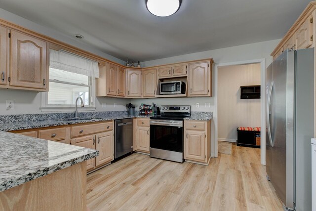 kitchen with appliances with stainless steel finishes, light brown cabinets, light wood-style floors, and light stone countertops