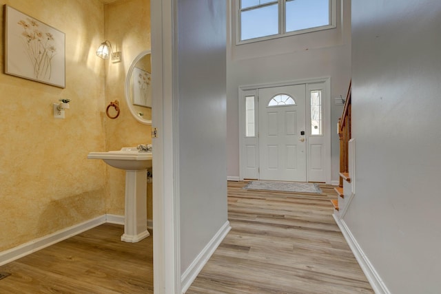 entrance foyer featuring a high ceiling, baseboards, and light wood finished floors