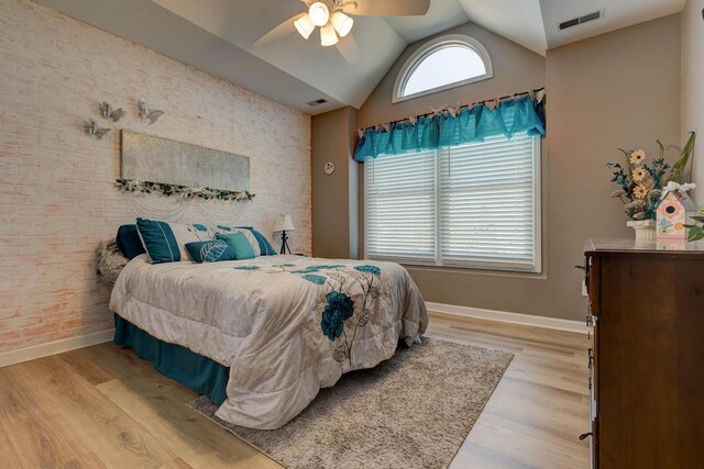 bedroom featuring light wood-style floors, visible vents, vaulted ceiling, and brick wall