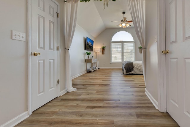 interior space featuring light wood-type flooring, baseboards, and lofted ceiling