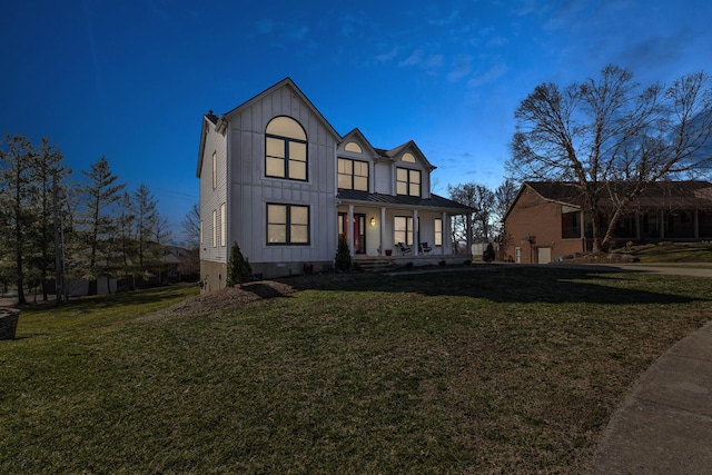 modern farmhouse style home featuring metal roof, a standing seam roof, a porch, board and batten siding, and a front yard