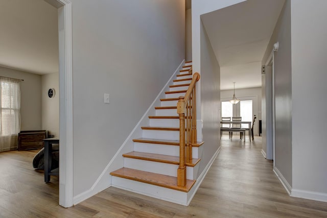 staircase featuring wood finished floors and baseboards