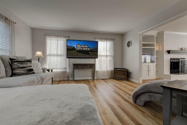 living area with a fireplace, wood finished floors, visible vents, and baseboards