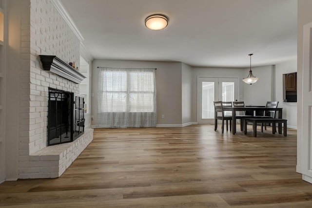 living room featuring light wood finished floors, a brick fireplace, and baseboards