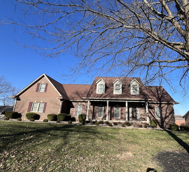 cape cod-style house with brick siding and a front yard