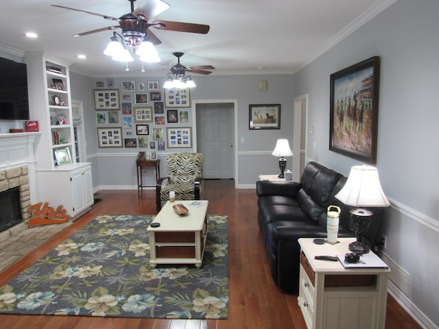 living area with baseboards, recessed lighting, dark wood-style flooring, ornamental molding, and a stone fireplace