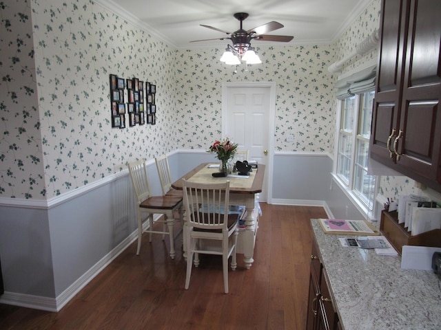 dining room featuring a wainscoted wall, dark wood-type flooring, crown molding, and wallpapered walls