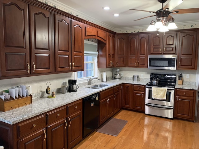 kitchen featuring light stone counters, ornamental molding, a sink, light wood-style floors, and appliances with stainless steel finishes