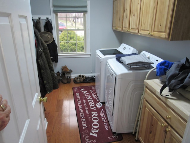 washroom with baseboards, cabinet space, separate washer and dryer, and wood finished floors