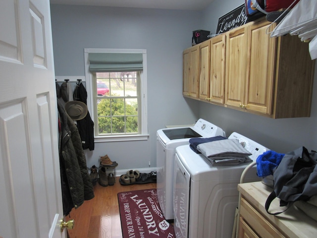 laundry room featuring wood finished floors, cabinet space, independent washer and dryer, and baseboards