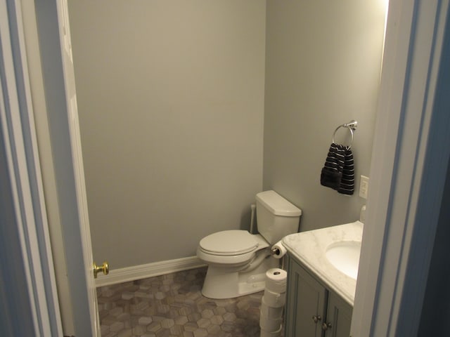 bathroom with baseboards, toilet, and vanity