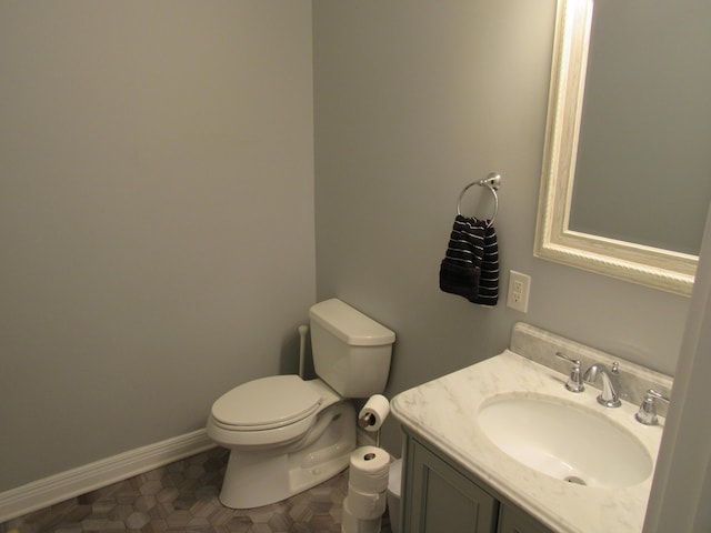 bathroom with toilet, vanity, and baseboards