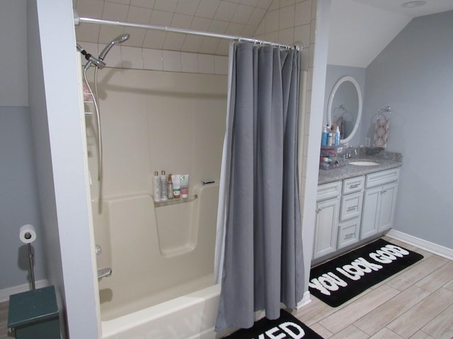 bathroom with vanity, baseboards, wood finish floors, lofted ceiling, and shower / bath combo with shower curtain