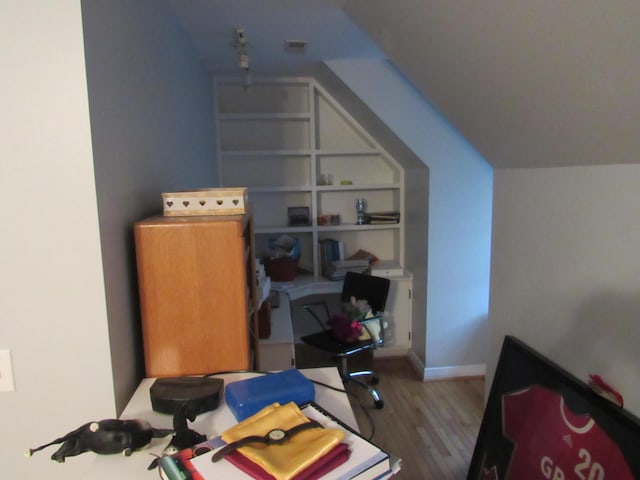 office area featuring built in shelves, baseboards, lofted ceiling, and wood finished floors