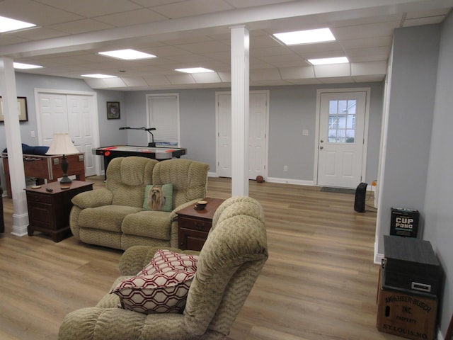 living room featuring a drop ceiling, baseboards, and wood finished floors