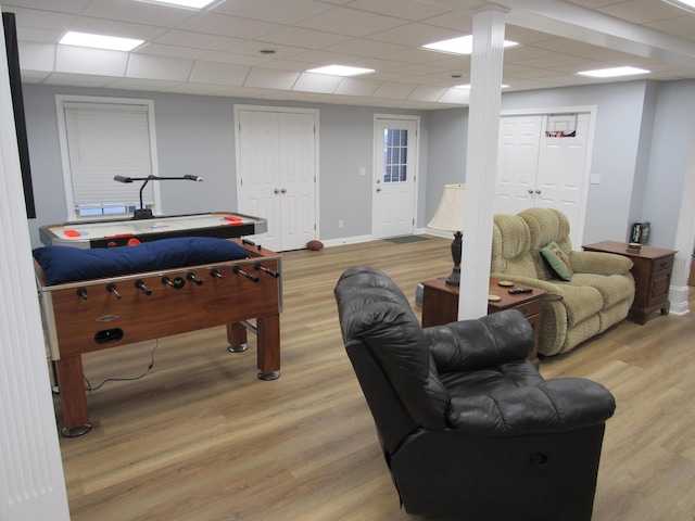 recreation room with a paneled ceiling, baseboards, and light wood finished floors