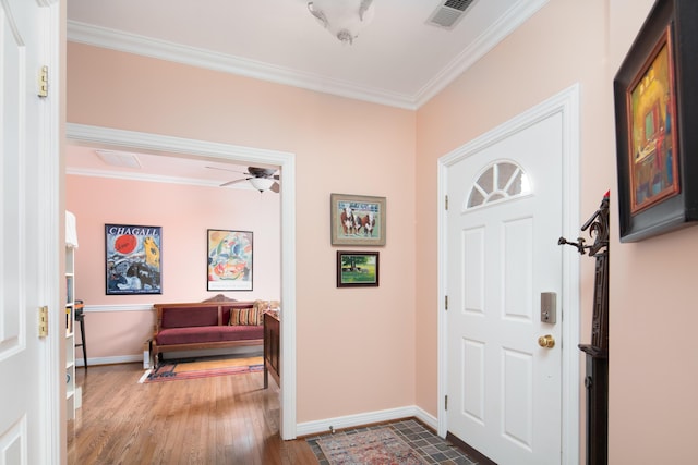 entryway with ceiling fan, wood finished floors, visible vents, baseboards, and crown molding