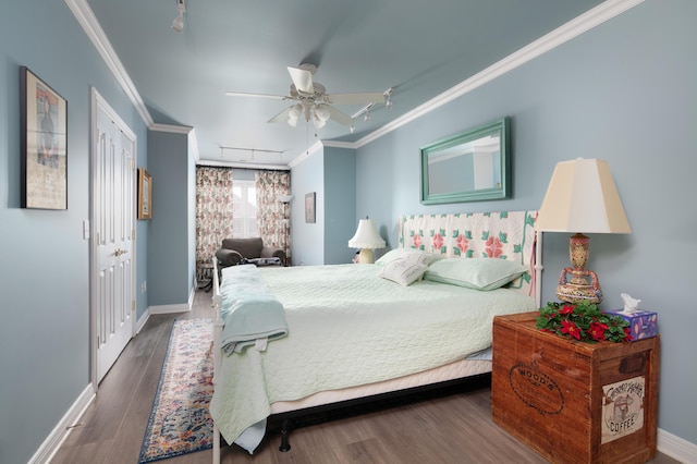 bedroom with track lighting, baseboards, crown molding, and wood finished floors