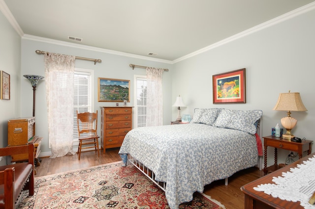 bedroom with visible vents, crown molding, and wood finished floors